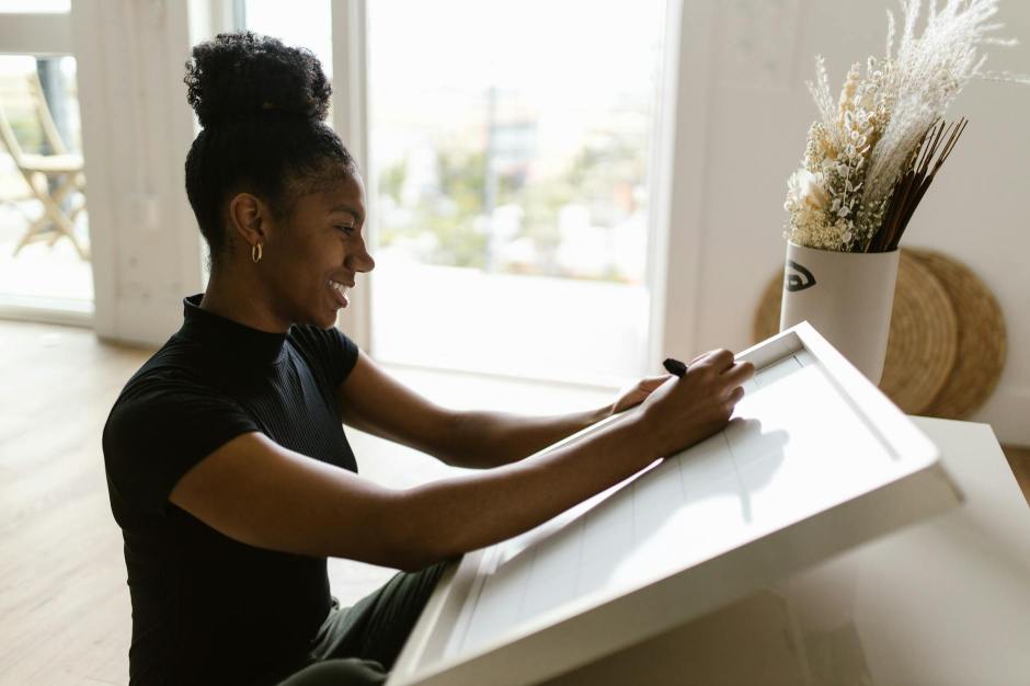 a smiling woman writing on a board while sitting on the floor